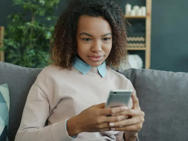 Mujer joven en el sofá de su casa revisando su celular