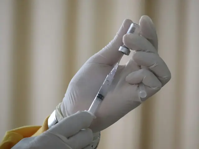 Manos con guantes cargando una jeringa desde un vial